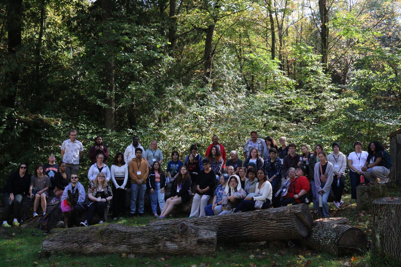 A photograph of a group of youth and adults in a nature setting in a forest.